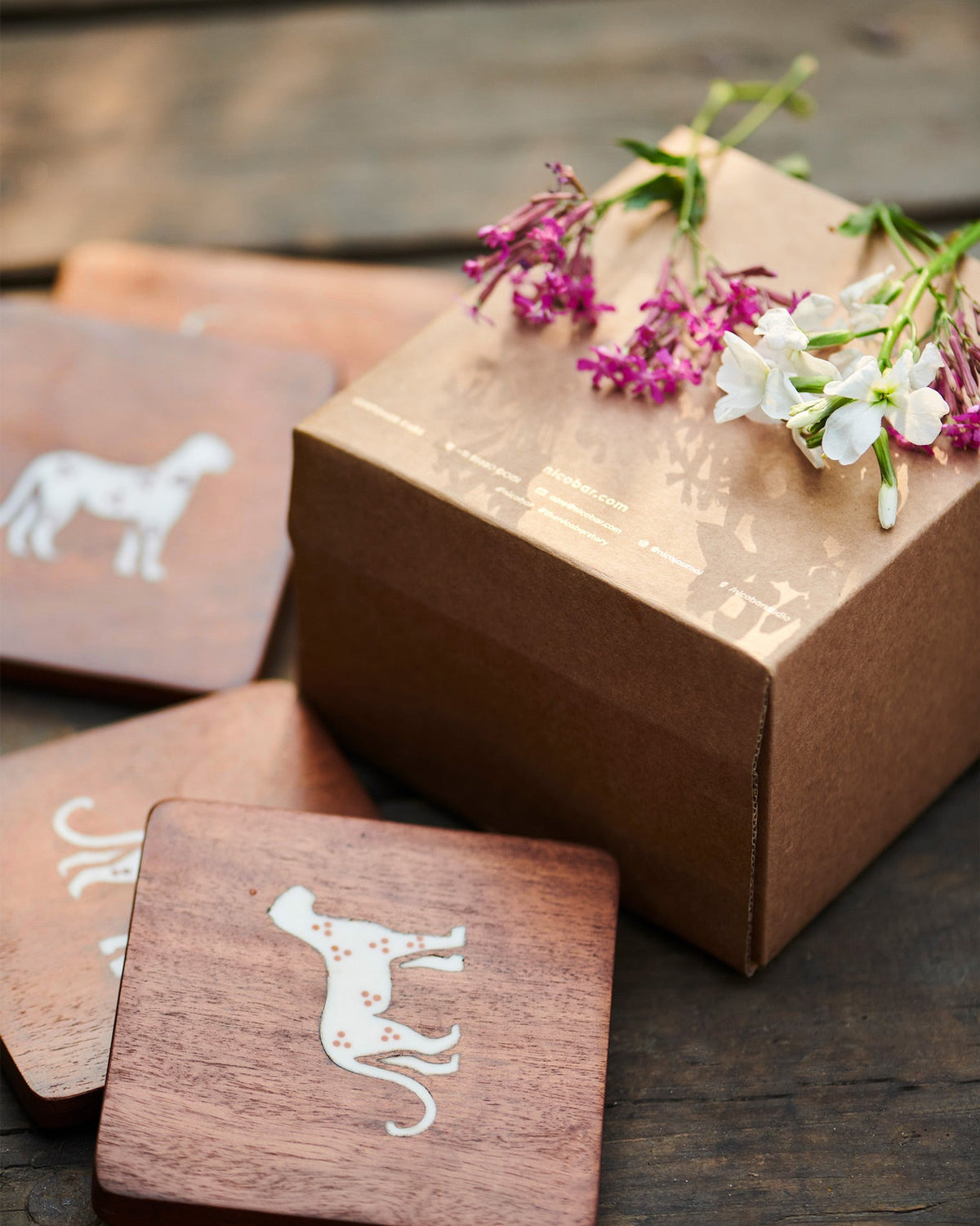 Cheetah Coaster with a white cheetah motif, beside a kraft gift box.