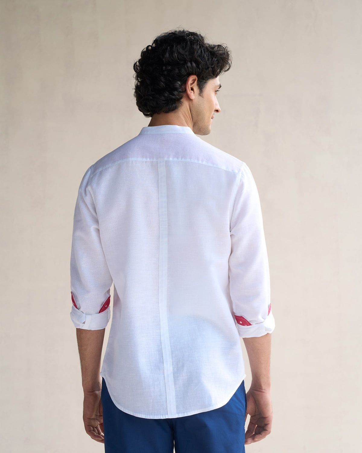 Back of a white Nawab shirt with red cuff linings, worn by a person.