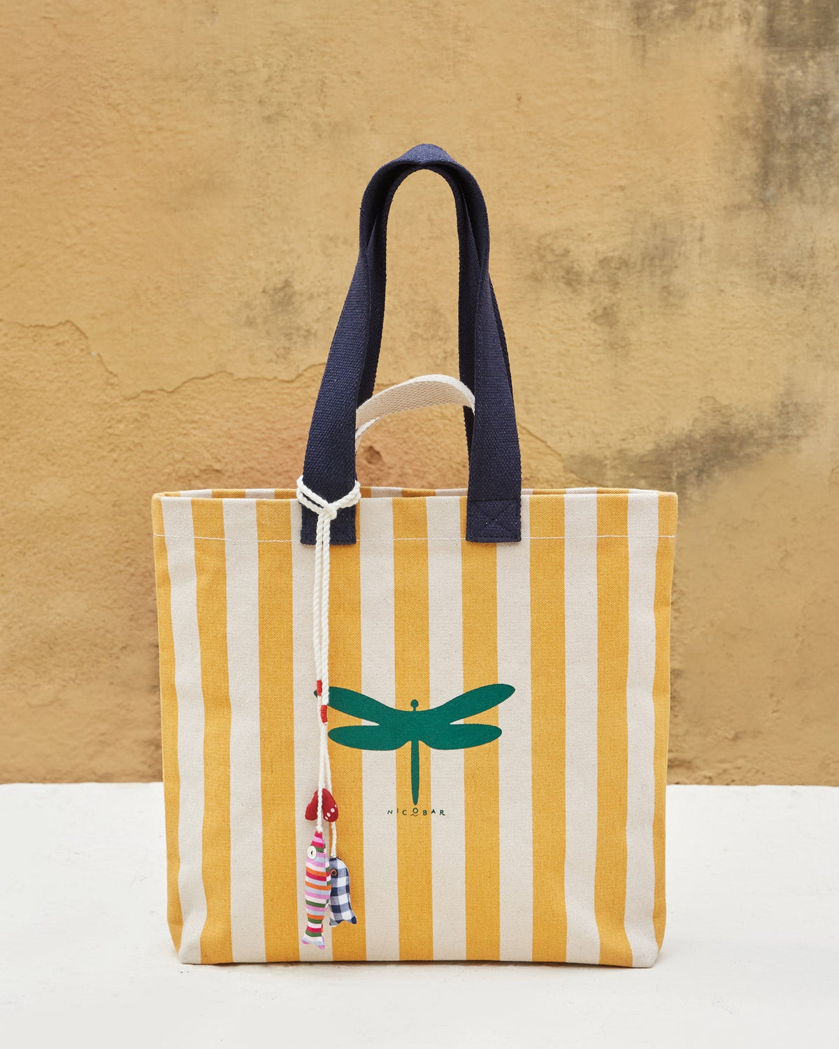 Bagan Stripe Tote with navy handles and a fabric charm on the cord.