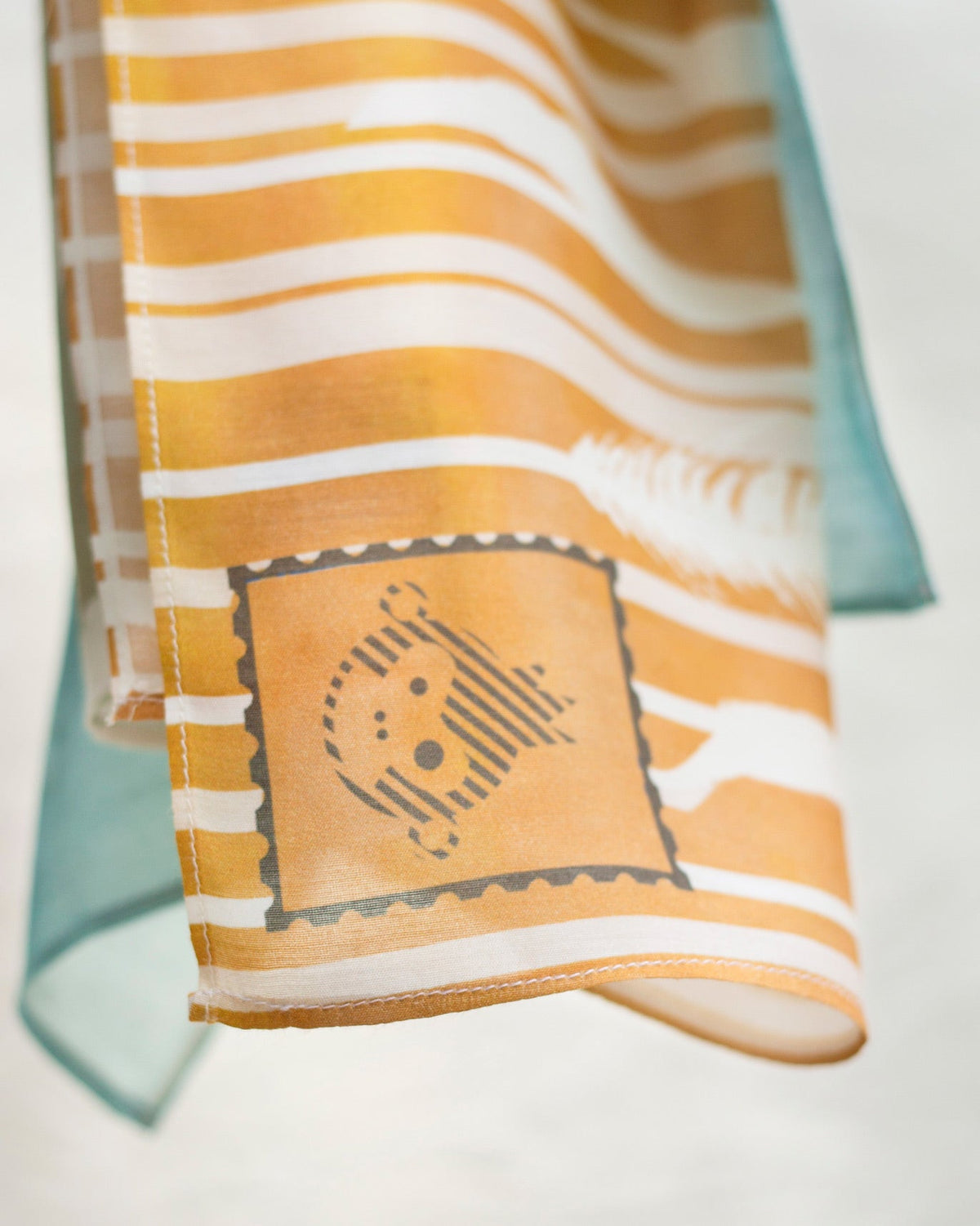 Close-up of Field of Wheat Scarf showing a stamp-style print on the hem.