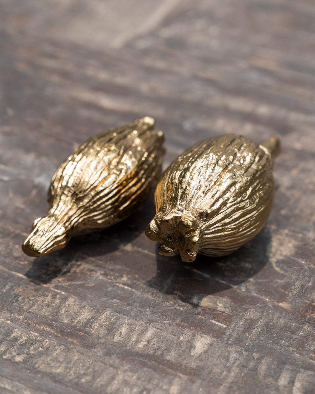 Pair of gold Poppy Salt & Pepper Shakers lying side by side.