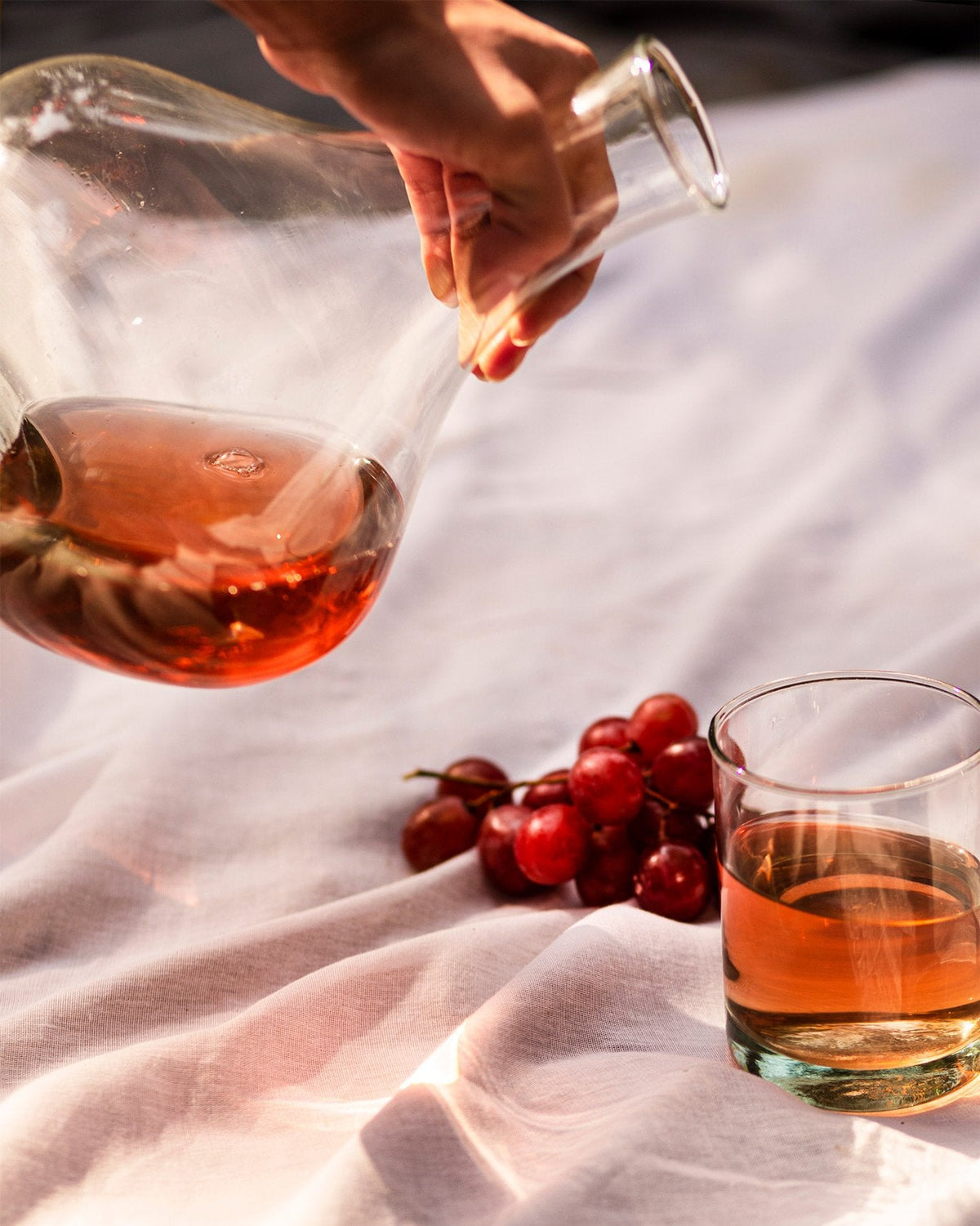 Hand pouring pink wine from the Wine Decanter with Stopper.