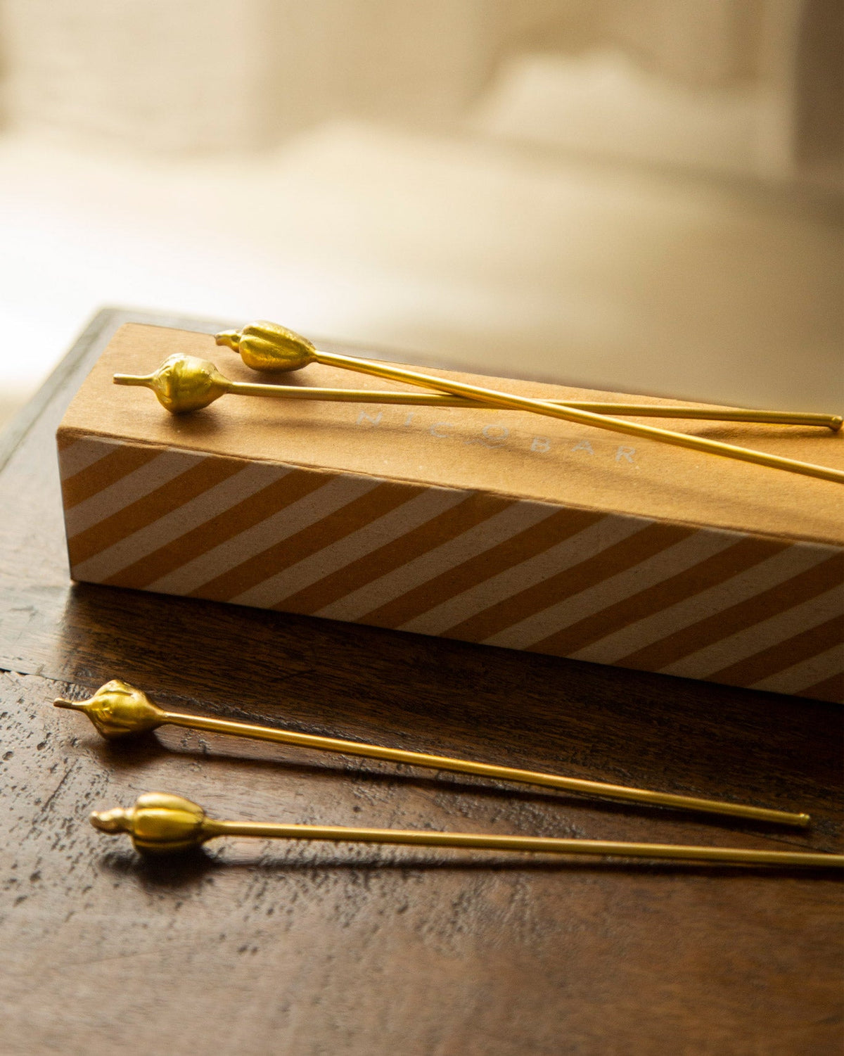 Cashew and Kokam Stirrers resting across a striped gift box.