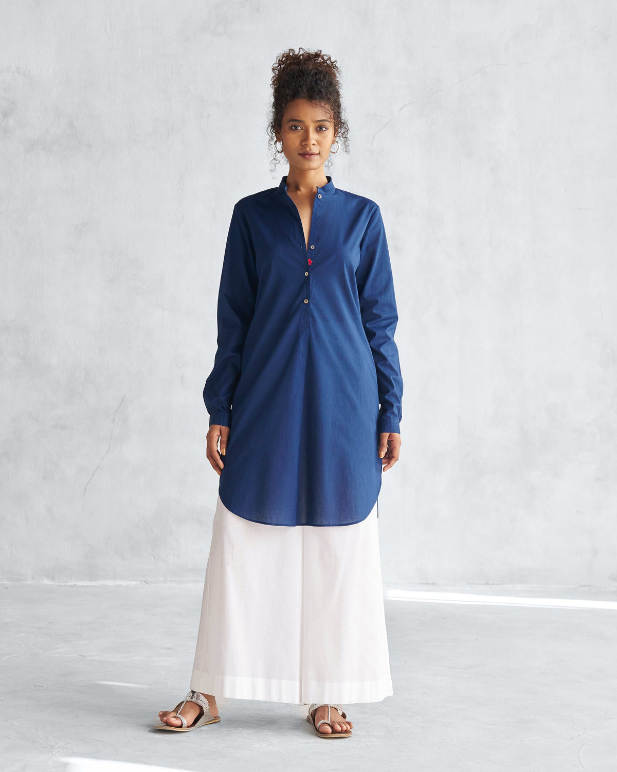 Person wearing a navy mid-length kurta with a curved shirt-tail hem.
