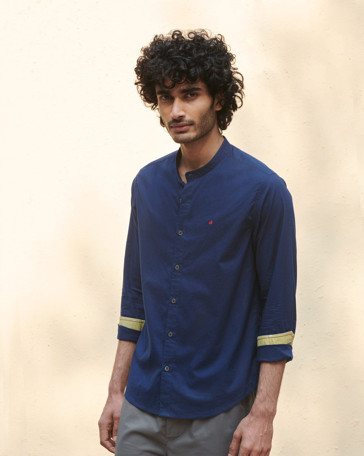 Side view of a navy Nawab Shirt with rolled sleeves and olive cuff lining.