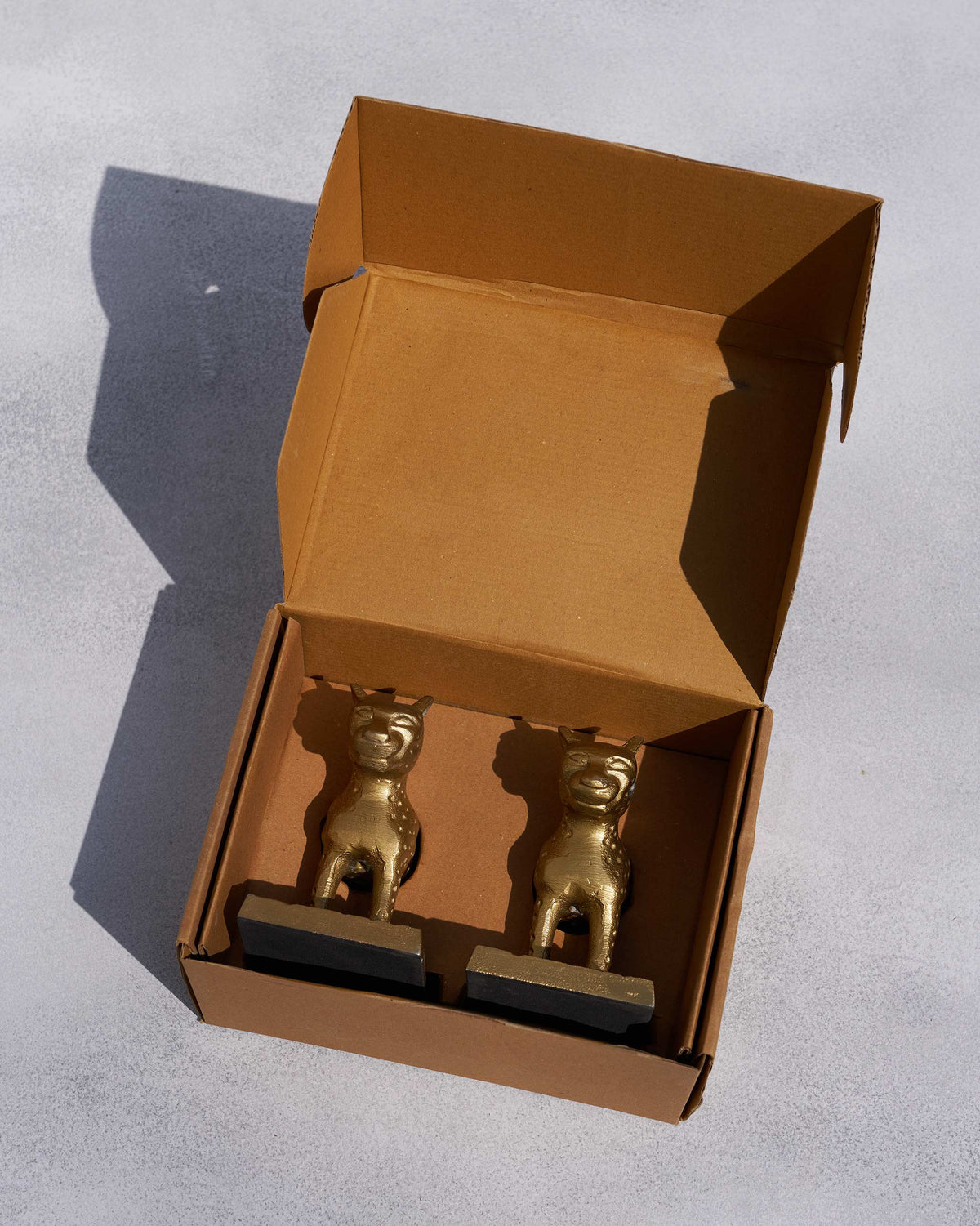 Leopard Bookends in brass-toned metal inside an open box.