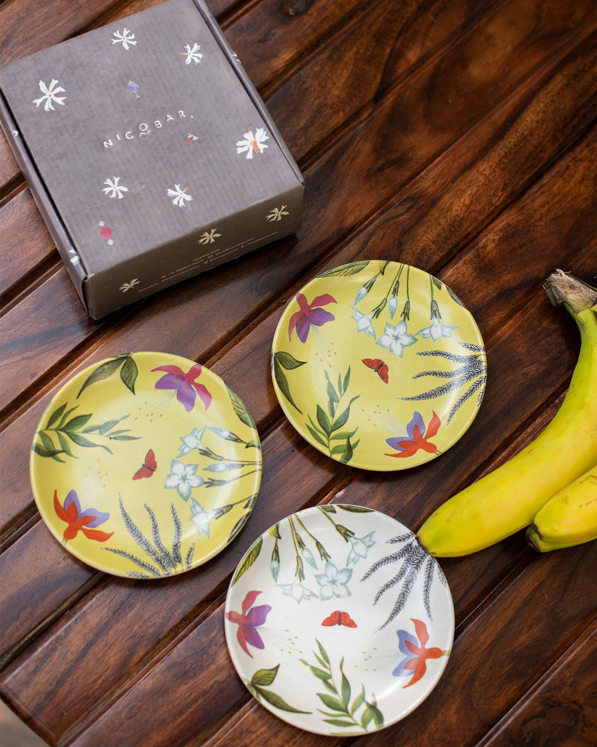 Botanical tea plates with tropical flowers and a red butterfly.