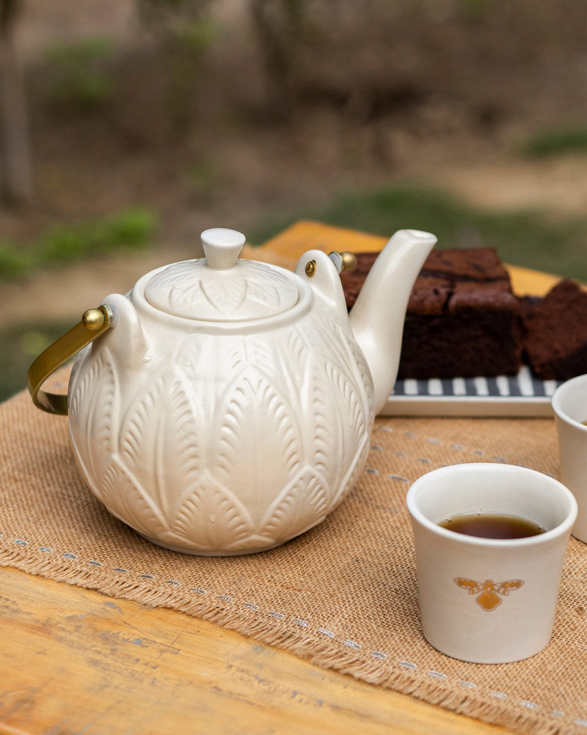 Teesta teapot with embossed leaves and a gold handle.