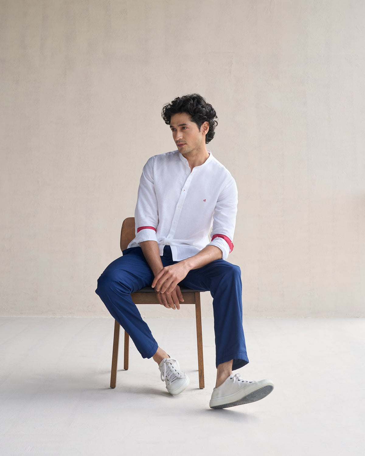 Person seated wearing a white Nawab shirt with red cuff linings.