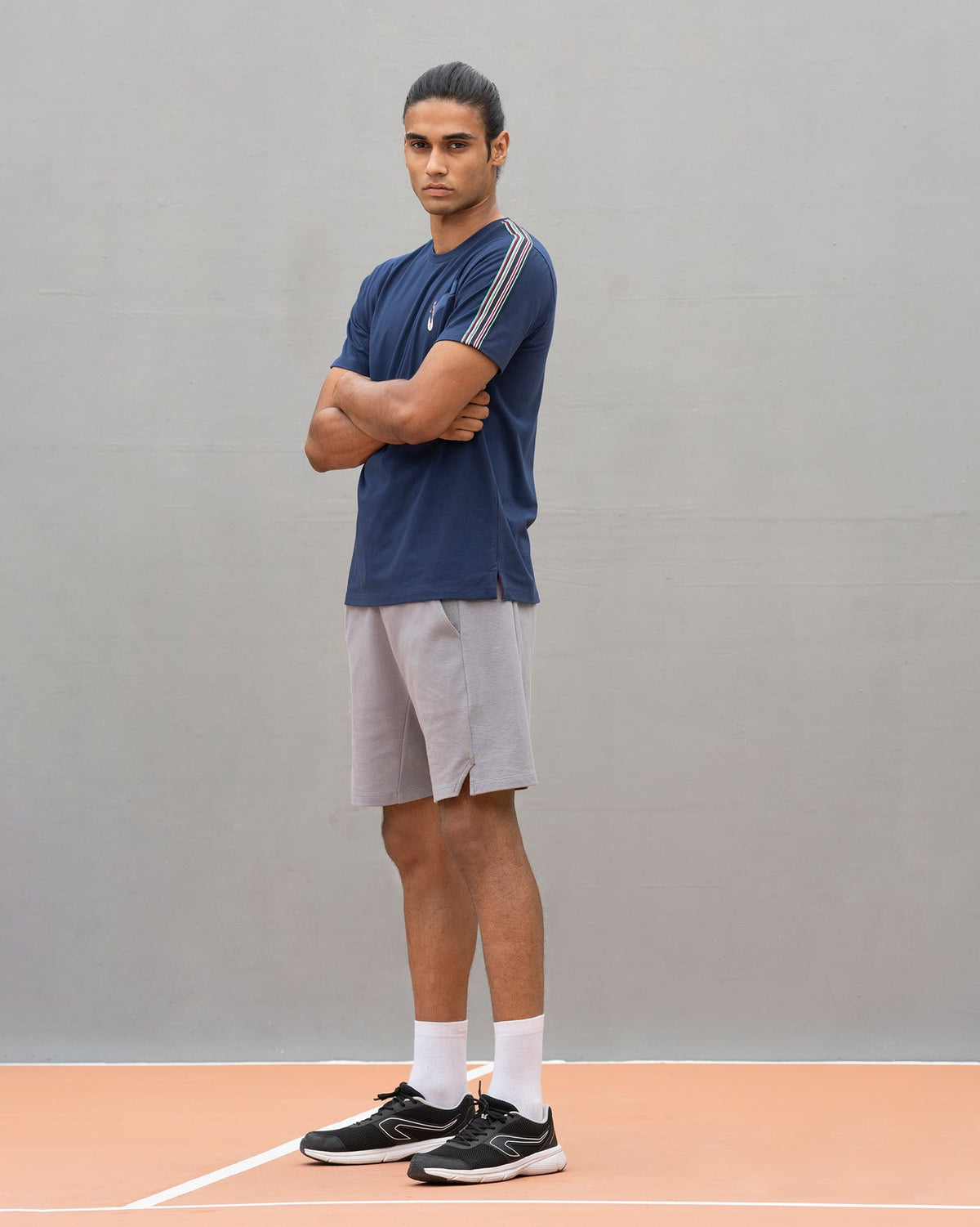 Person with arms crossed in a navy Nico crew neck t-shirt.