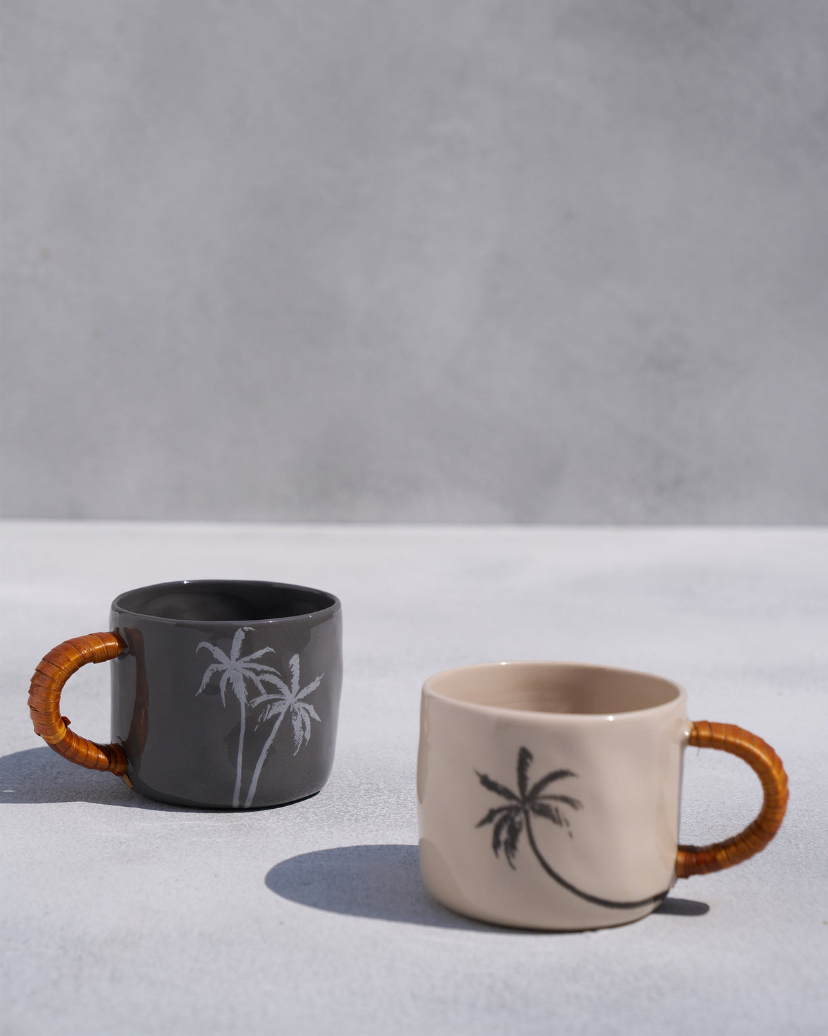 Pair of Mandovi mugs in charcoal and ivory with palm tree prints.