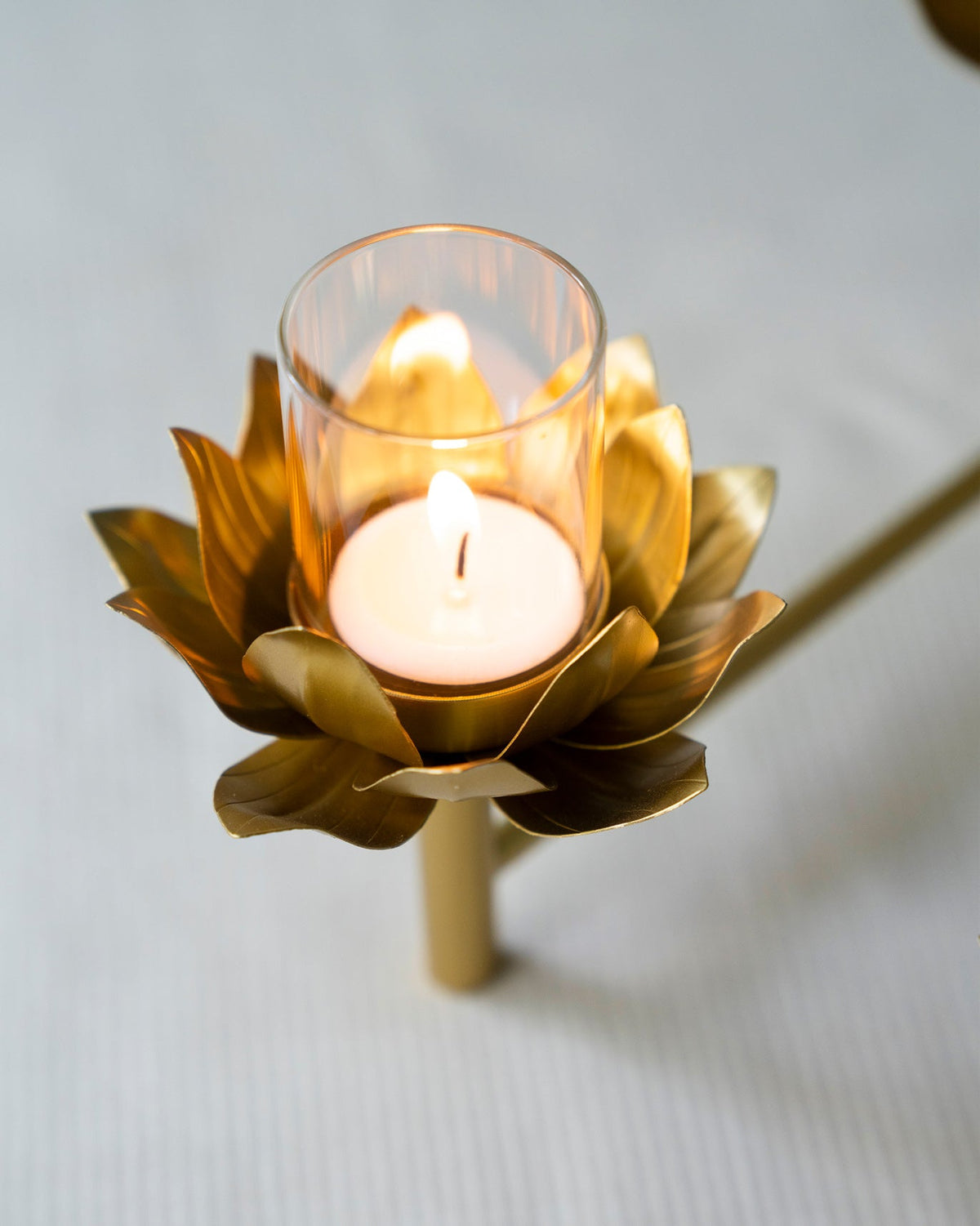 Close-up of a Sitara tealight holder with a lit tealight in its gold lotus cup.