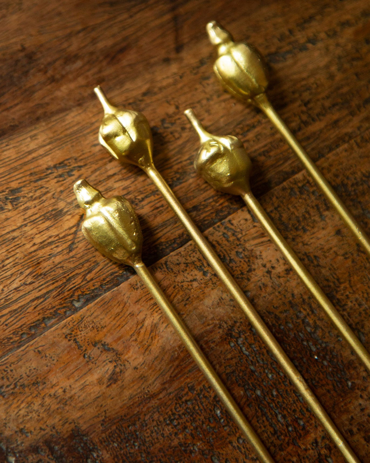 Close-up of Cashew and Kokam Stirrers showing their gold-finished tops.