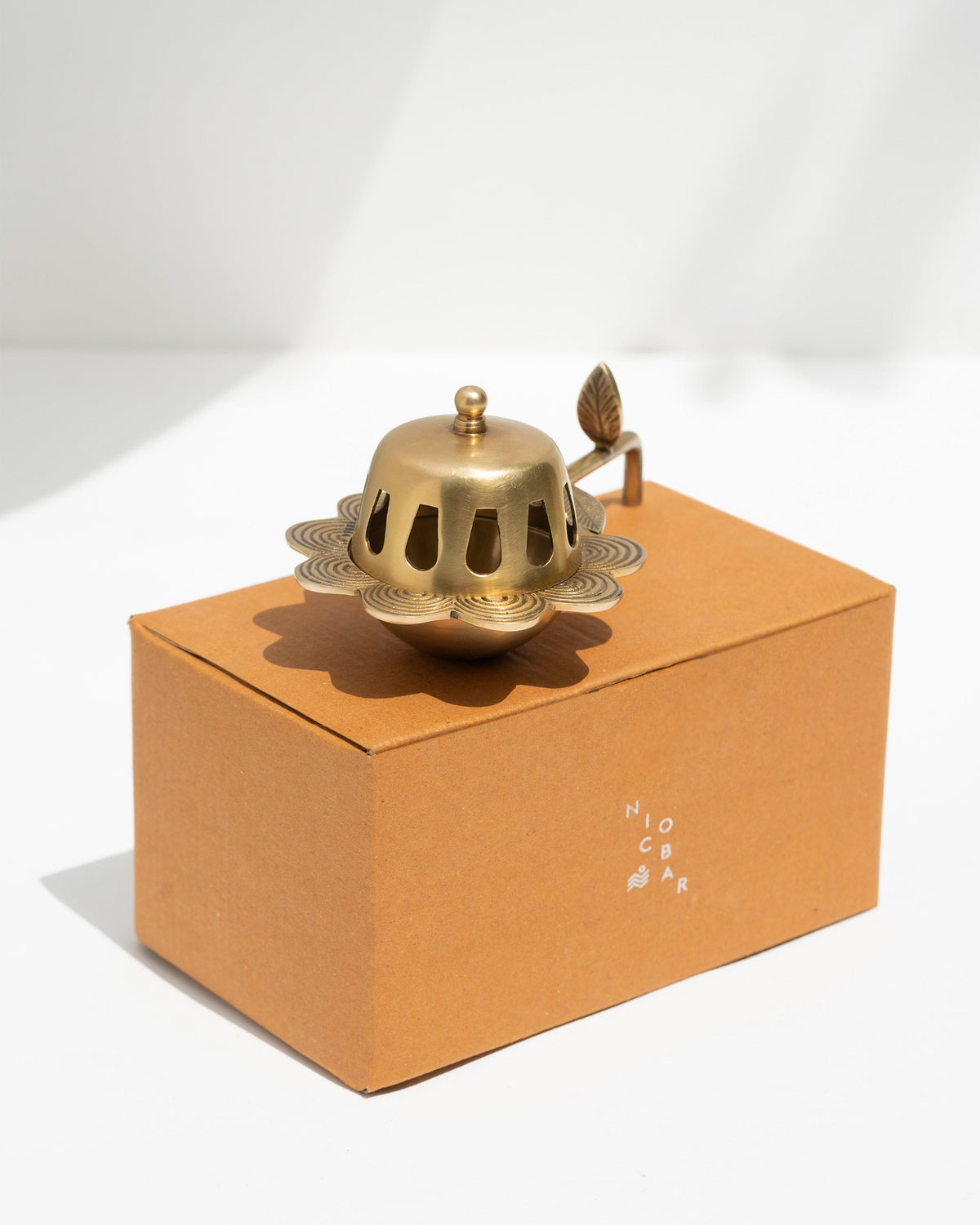 Alpine Dhuna in brass sitting on a kraft Nicobar box.