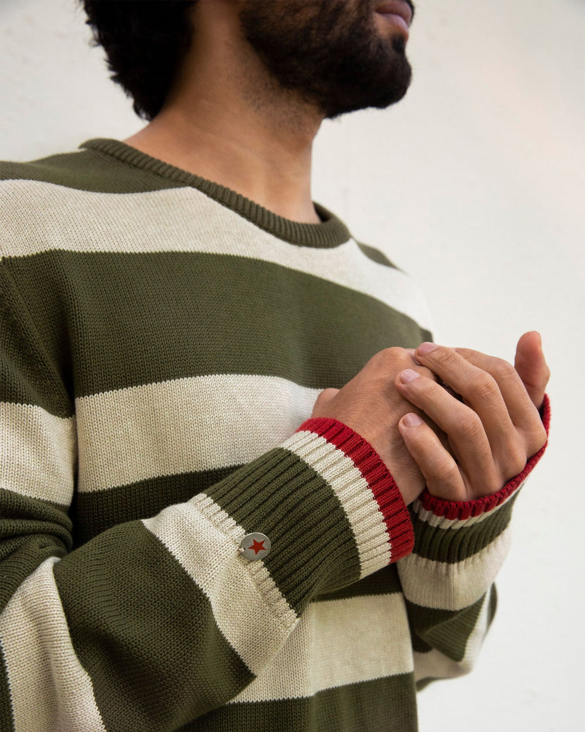 Close-up of the Round Neck Sweater cuff with red trim and a small star button.