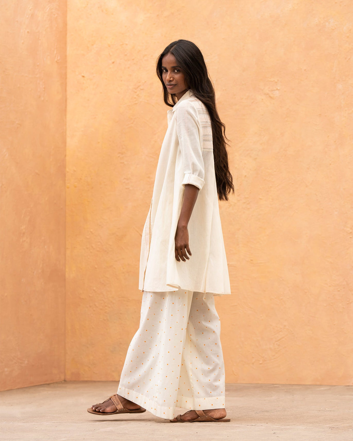 Side view of an ivory Back Flayer Top with an A-line silhouette.