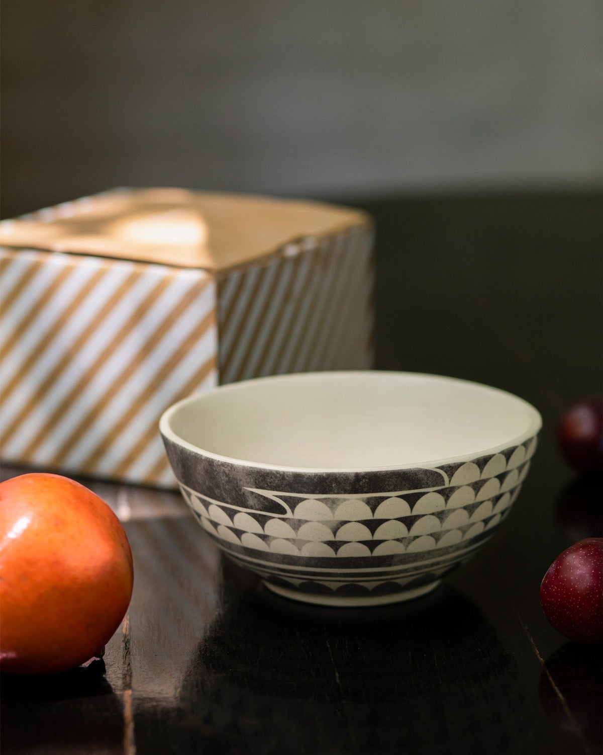 Aasma Curry Bowl in cream beside a striped box.