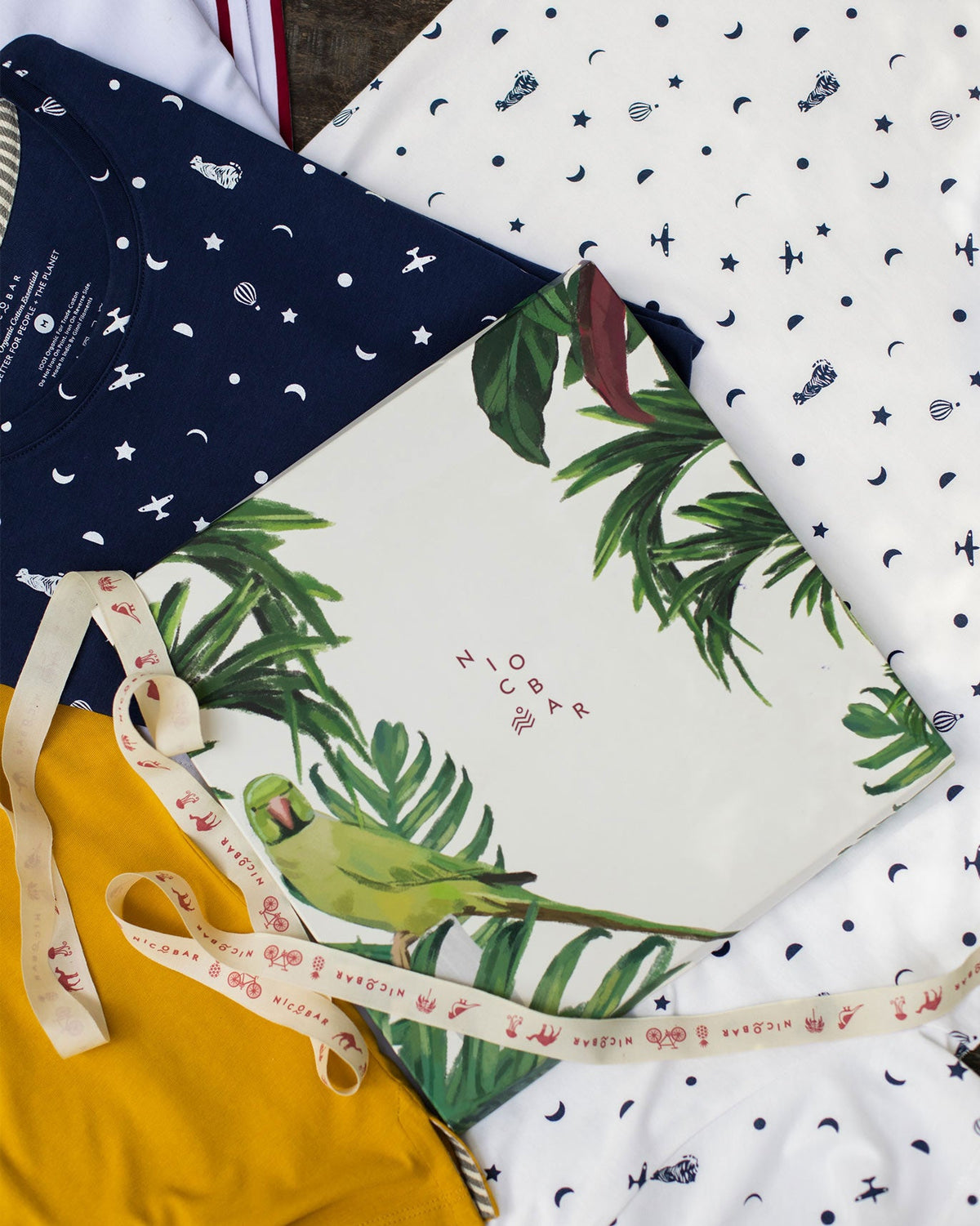 Flat lay of a folded white printed tee beside a Nicobar box.