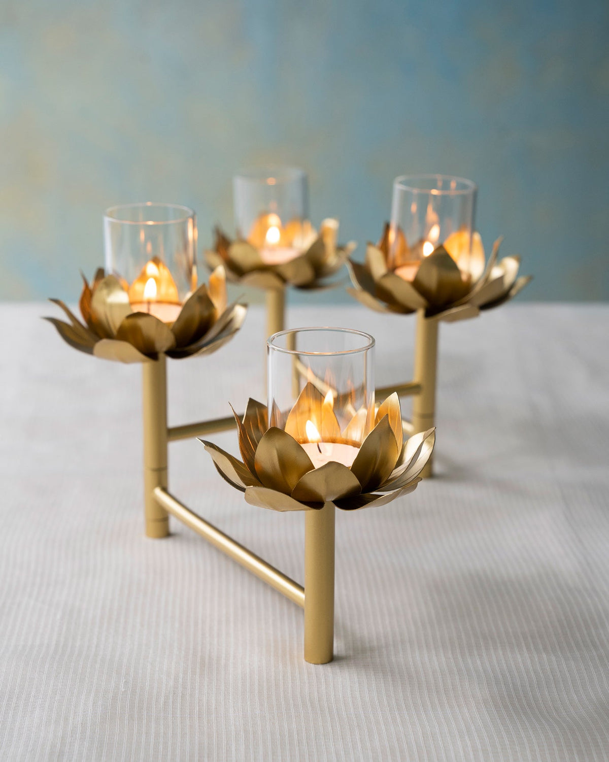 Sitara tealight stand with four lit holders, one in the foreground.