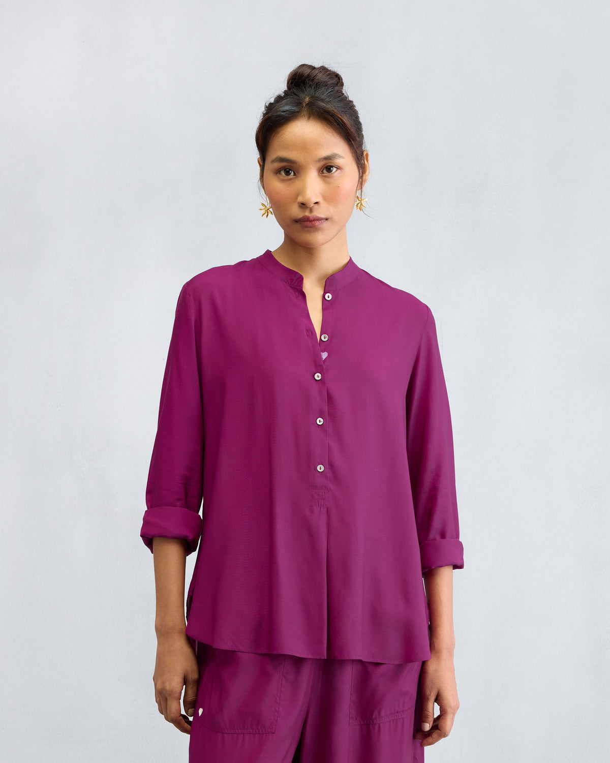 Person wearing a mulberry mandarin collar top with a button placket.