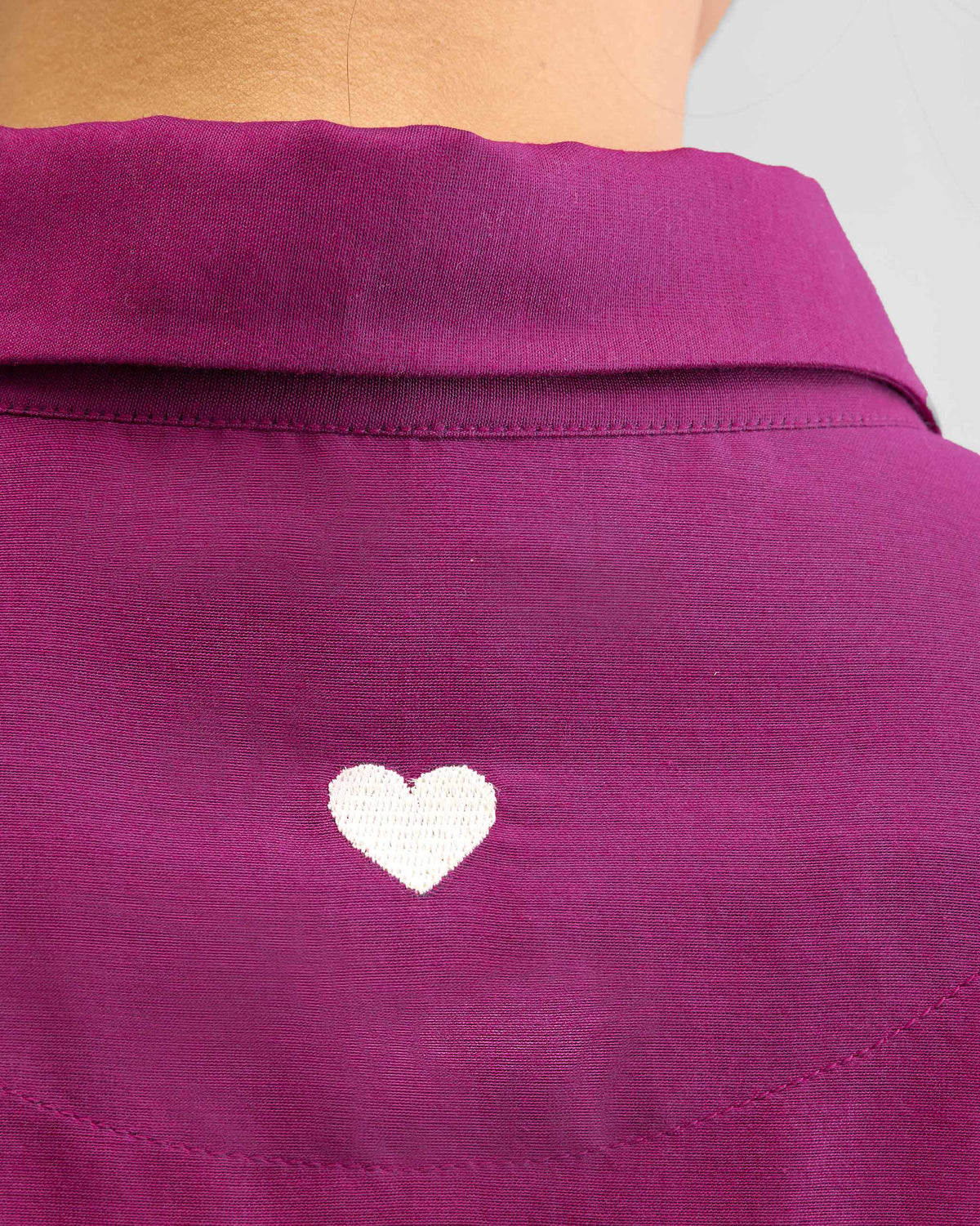 Close-up of a white heart embroidered on the back of a mulberry shirt.