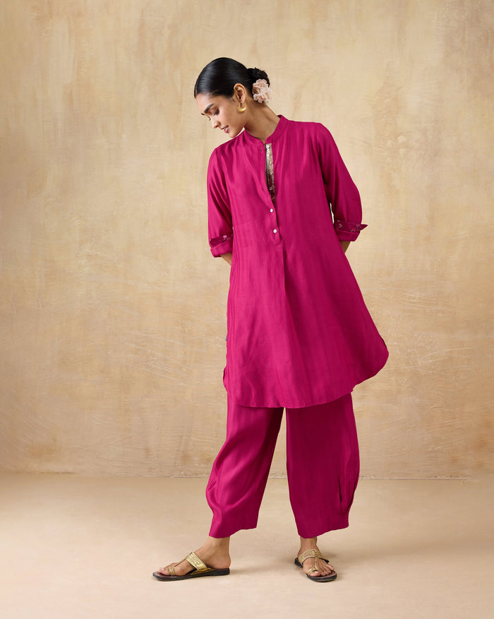 Person wearing a berry pink long kurta set with matching wide-leg pants.