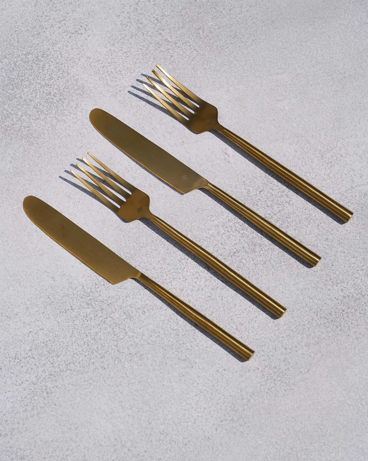 Four gold Sitara forks and knives arranged diagonally.