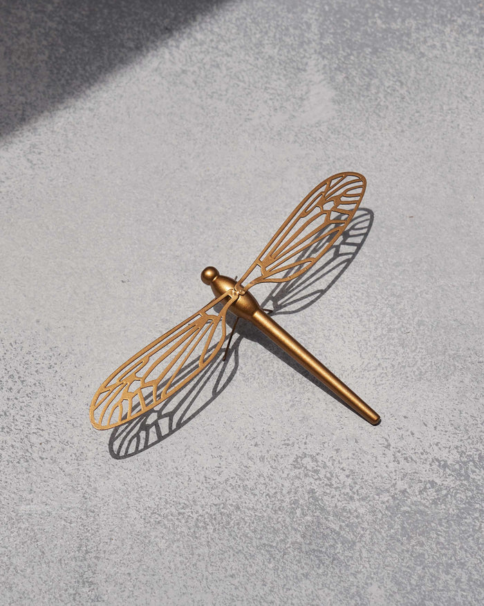 Large dragonfly accent piece in gold with cut-out wing veins, laid at an angle.