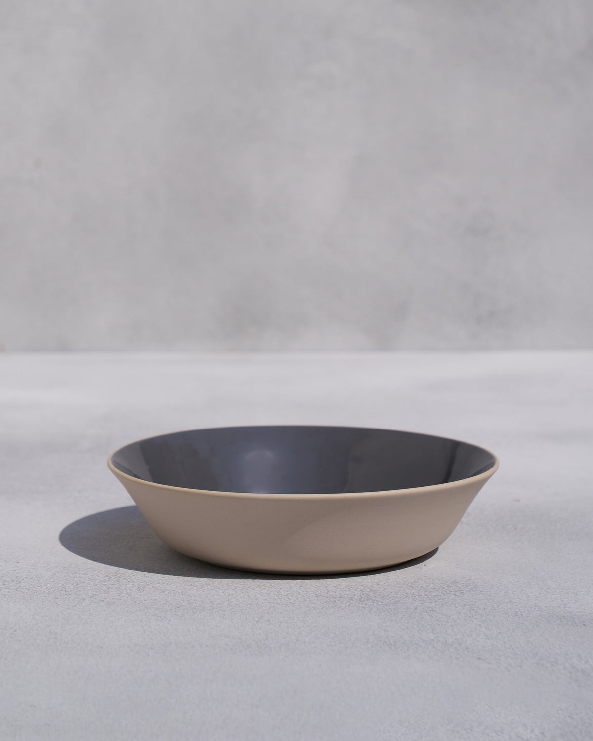 Side view of Kangra Vegetable Bowl with a tan outer rim and grey interior.