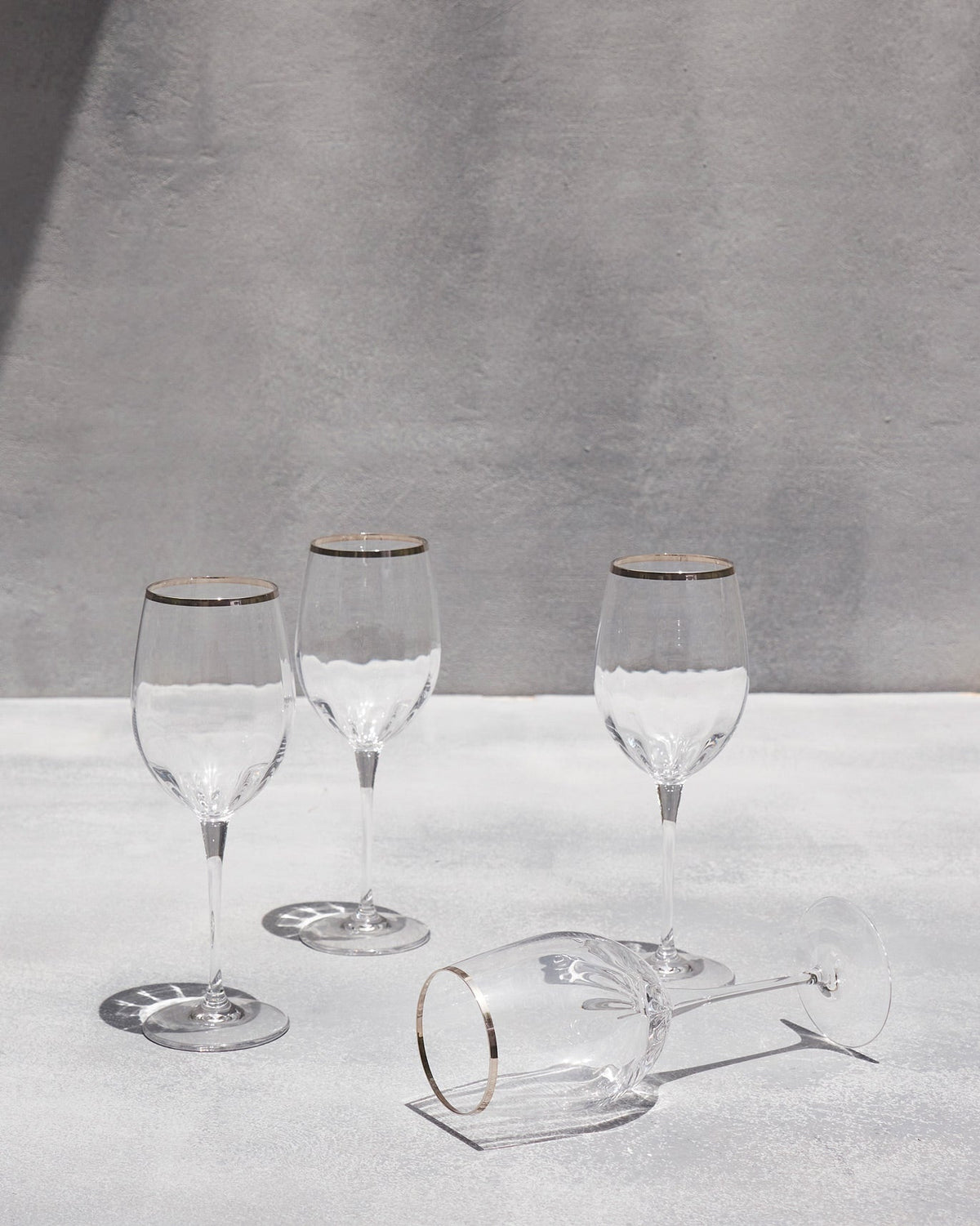 Celeste red wine glass lying on its side beside three upright glasses.