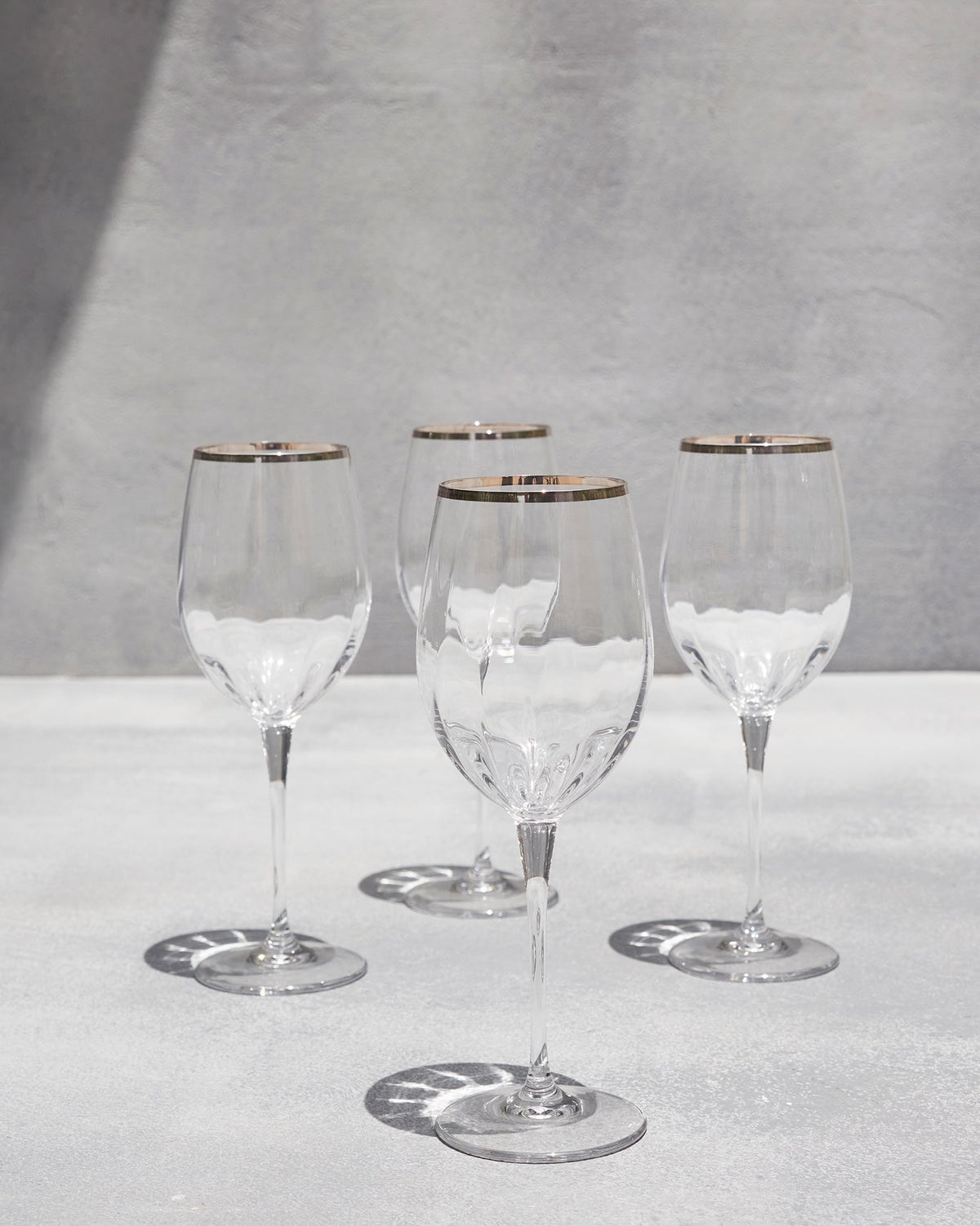 Four Celeste red wine glasses arranged in a loose cluster on a pale surface.