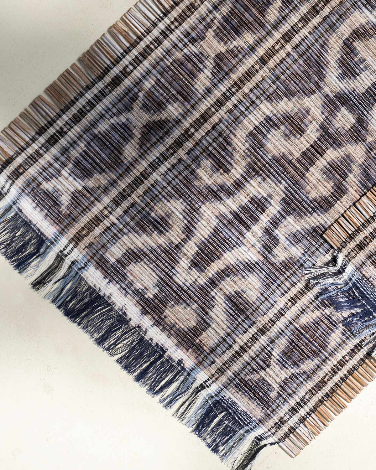 Close-up of Sitara Ikat Placemat weave in charcoal with cream motifs and fringed edges.