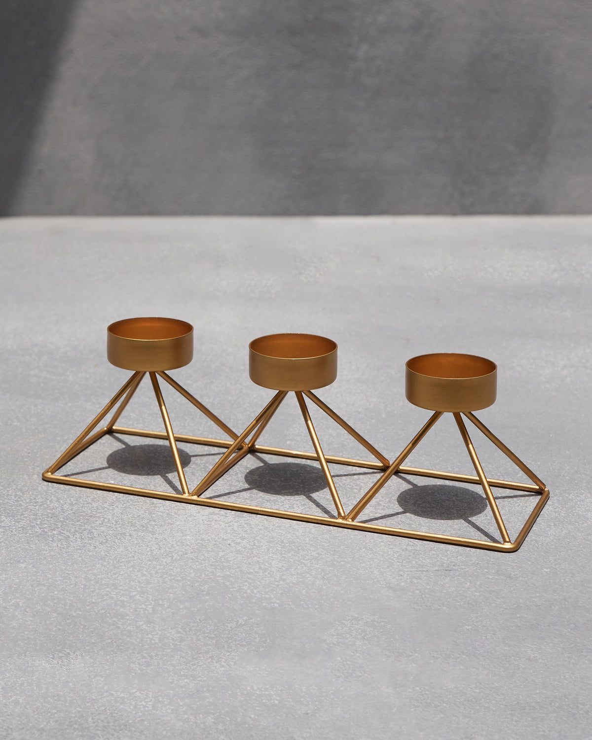 Side view of Myra Tealight Stand with three gold cups on triangular frames.