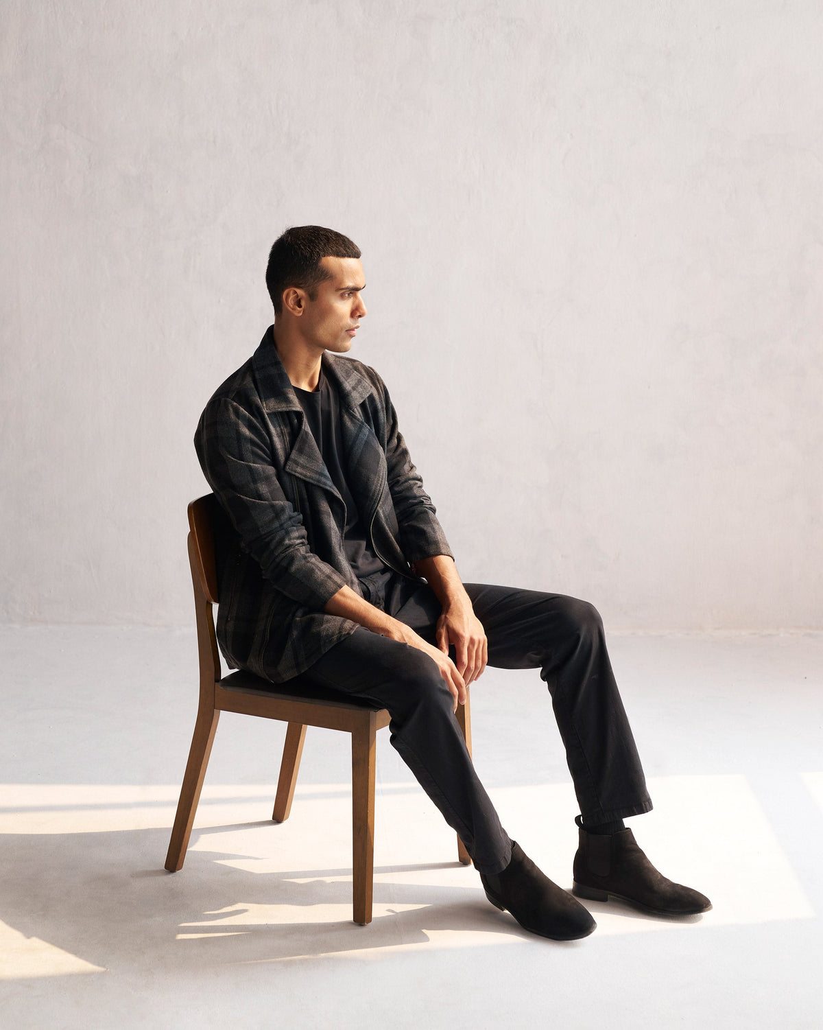 Person seated in a black and grey checked Woollen Knotch Collar Jacket, turned to the side.