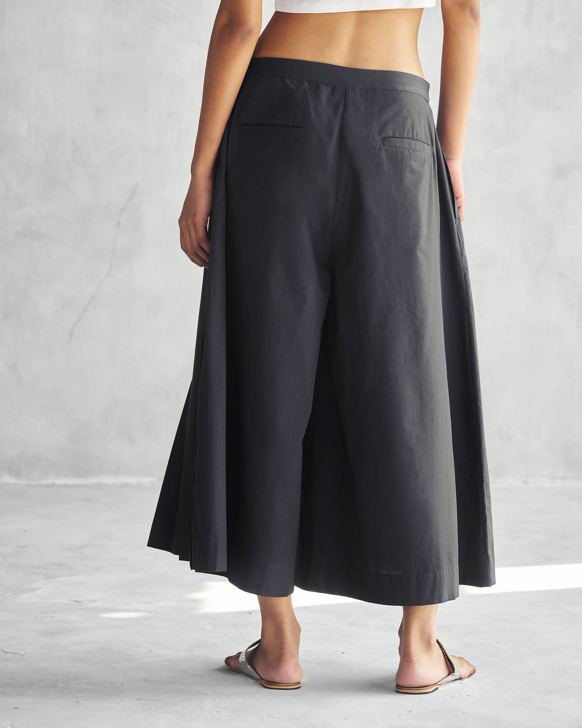Back of black Pleated Flare Culottes with welt back pockets.