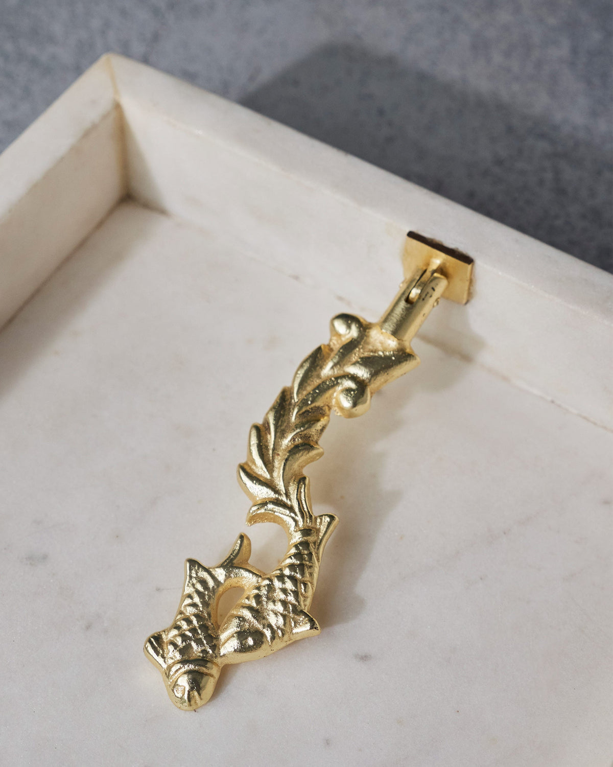 Close-up of the gold fish-motif upright on a Mahi Napkin Holder.