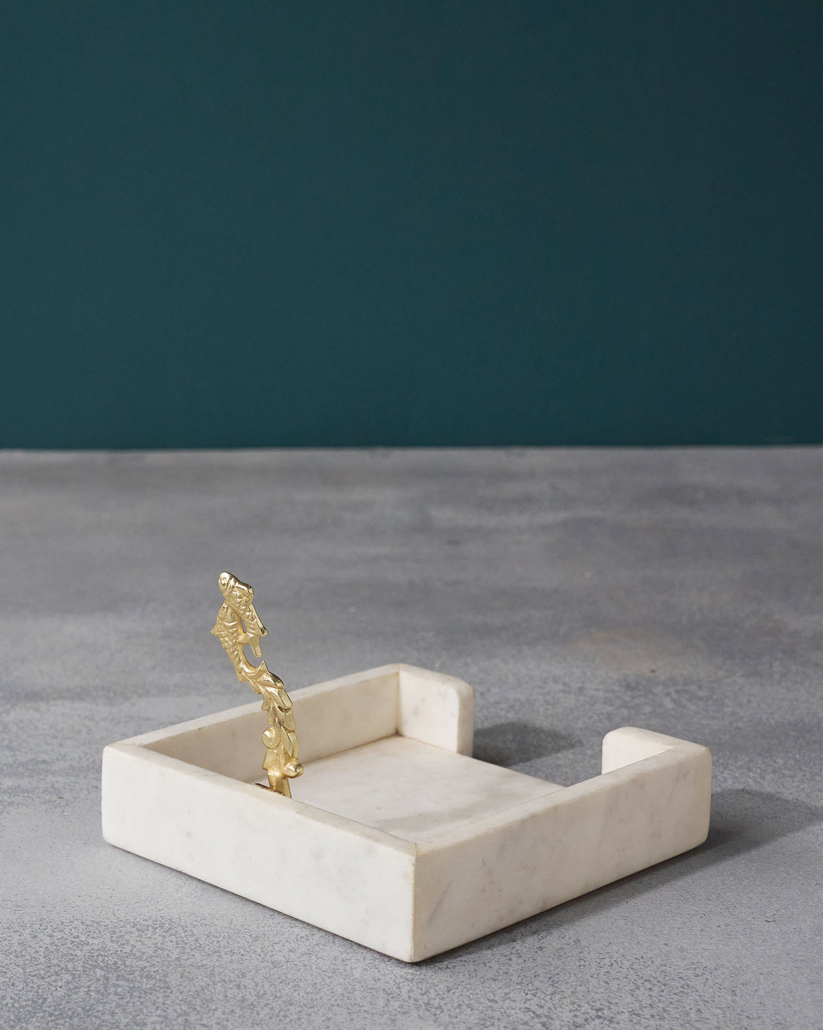 Mahi Napkin Holder with a gold fish-motif upright at one end.