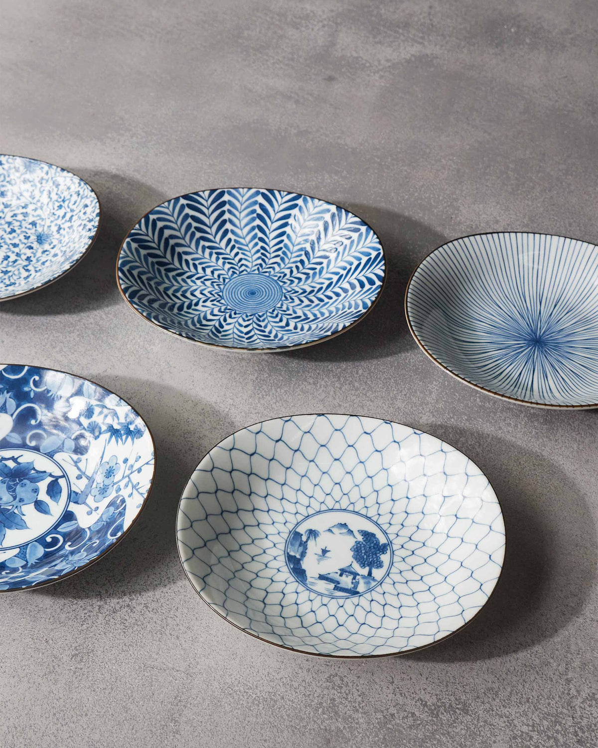 Donburi bowls from above showing lattice, floral, radial, and leaf blue patterns.