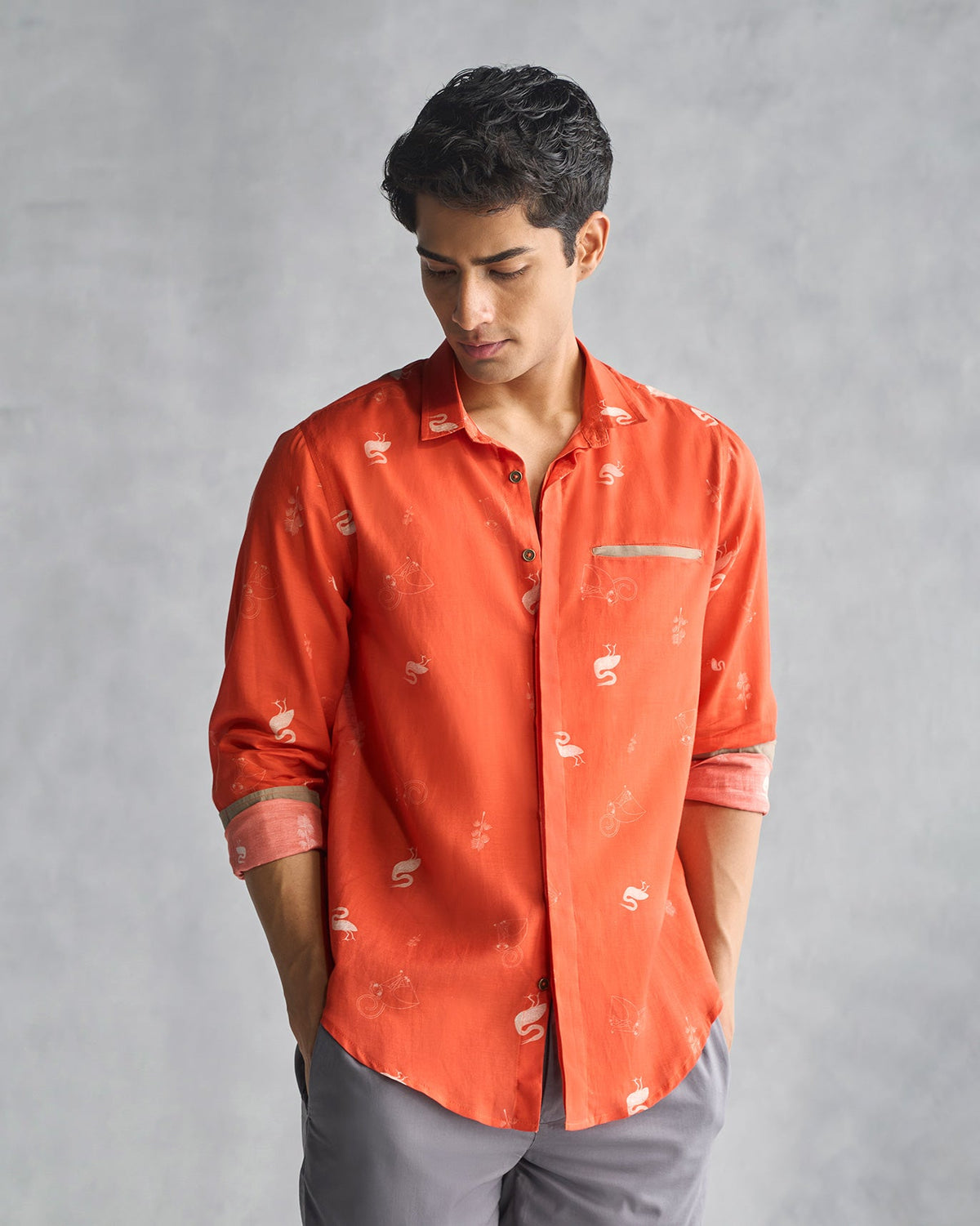 Person wearing a buttoned rust Paradise Shirt with rolled sleeves.