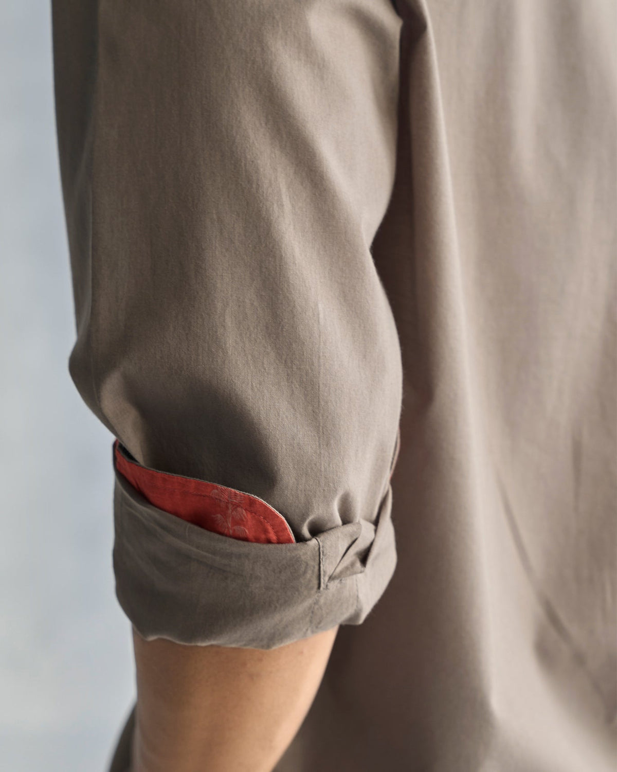 Close-up of a rolled Plateau shirt sleeve showing red lining inside the cuff.