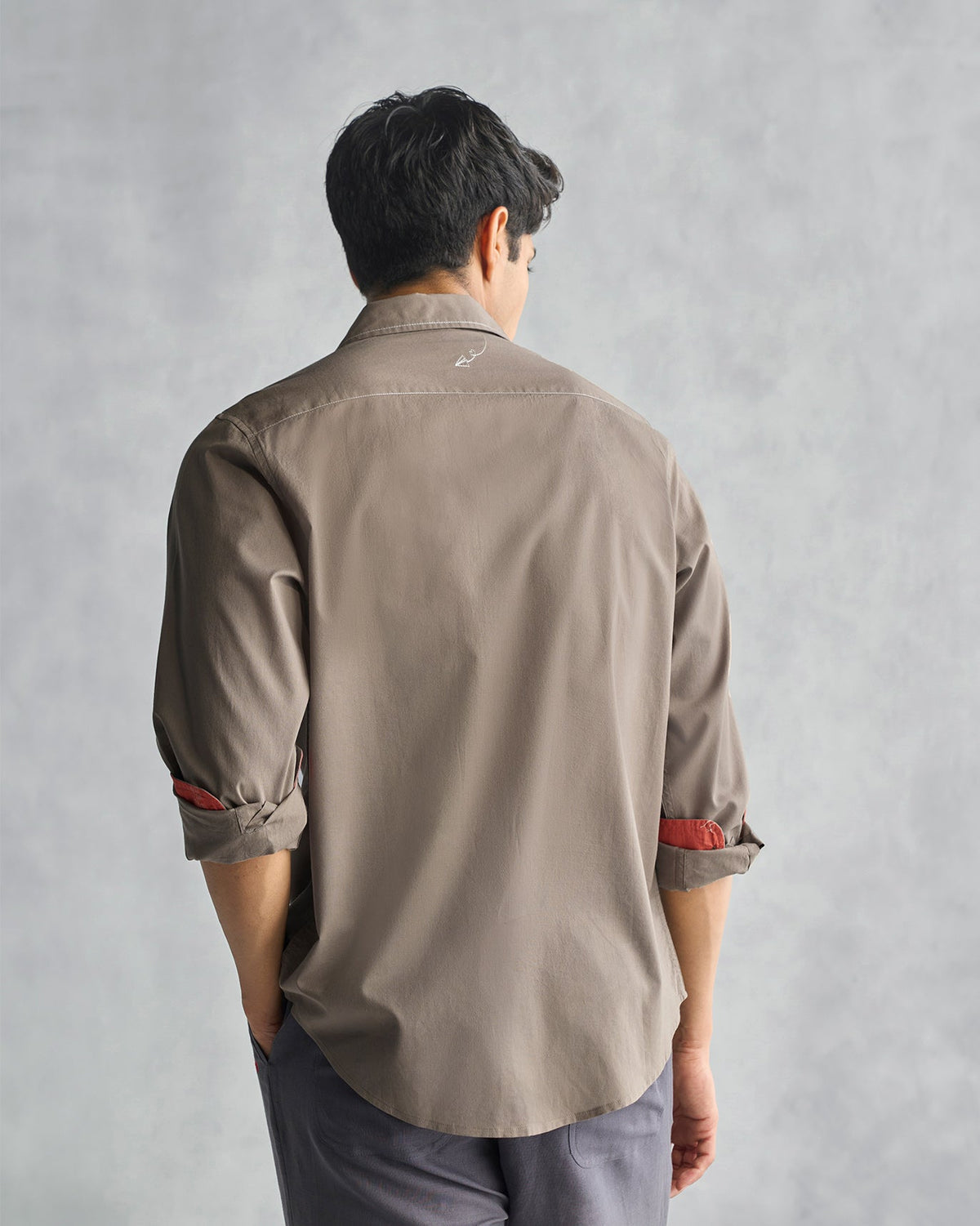 Back of an oak brown Plateau shirt worn by a person, sleeves rolled with red lining.