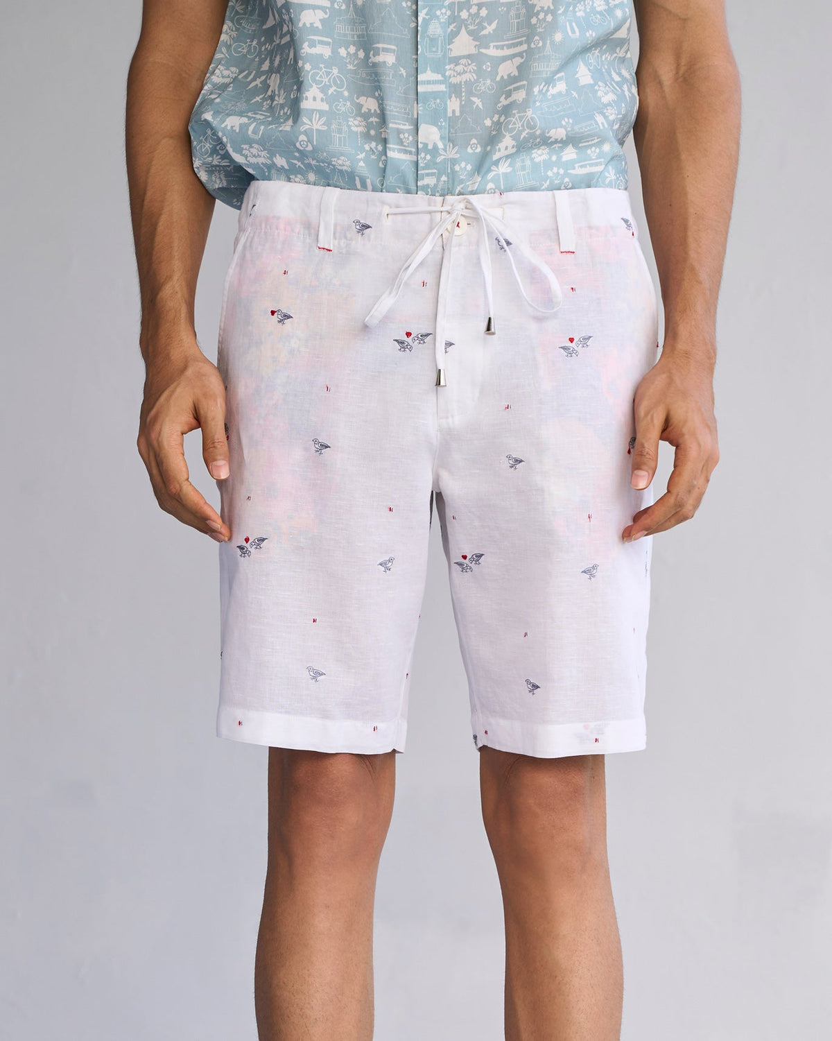 Person wearing white Jambo Shorts with small embroidered birds.