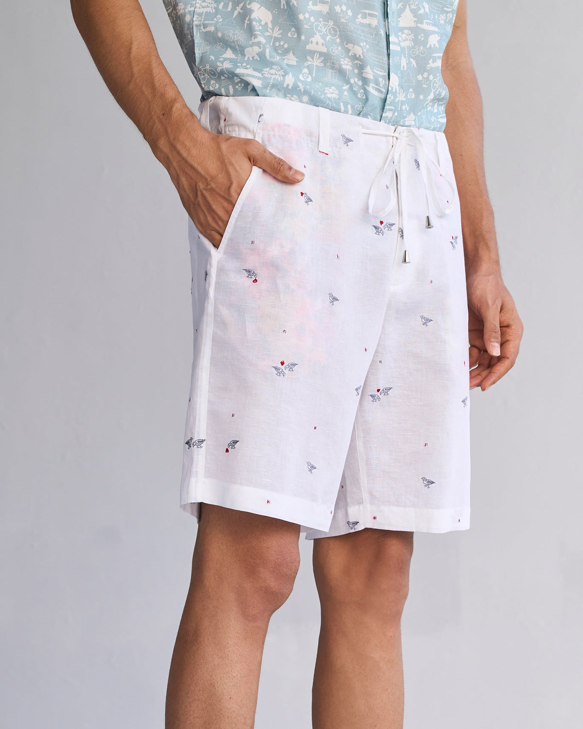 Side view of white Jambo Shorts worn by a person, hand in pocket.