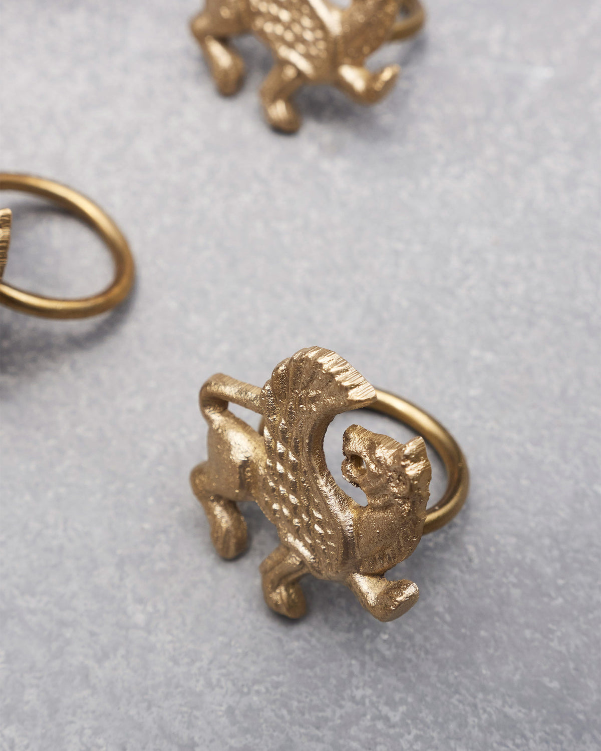 Close-up of a brass Chinthe Napkin Ring with a winged creature figure.
