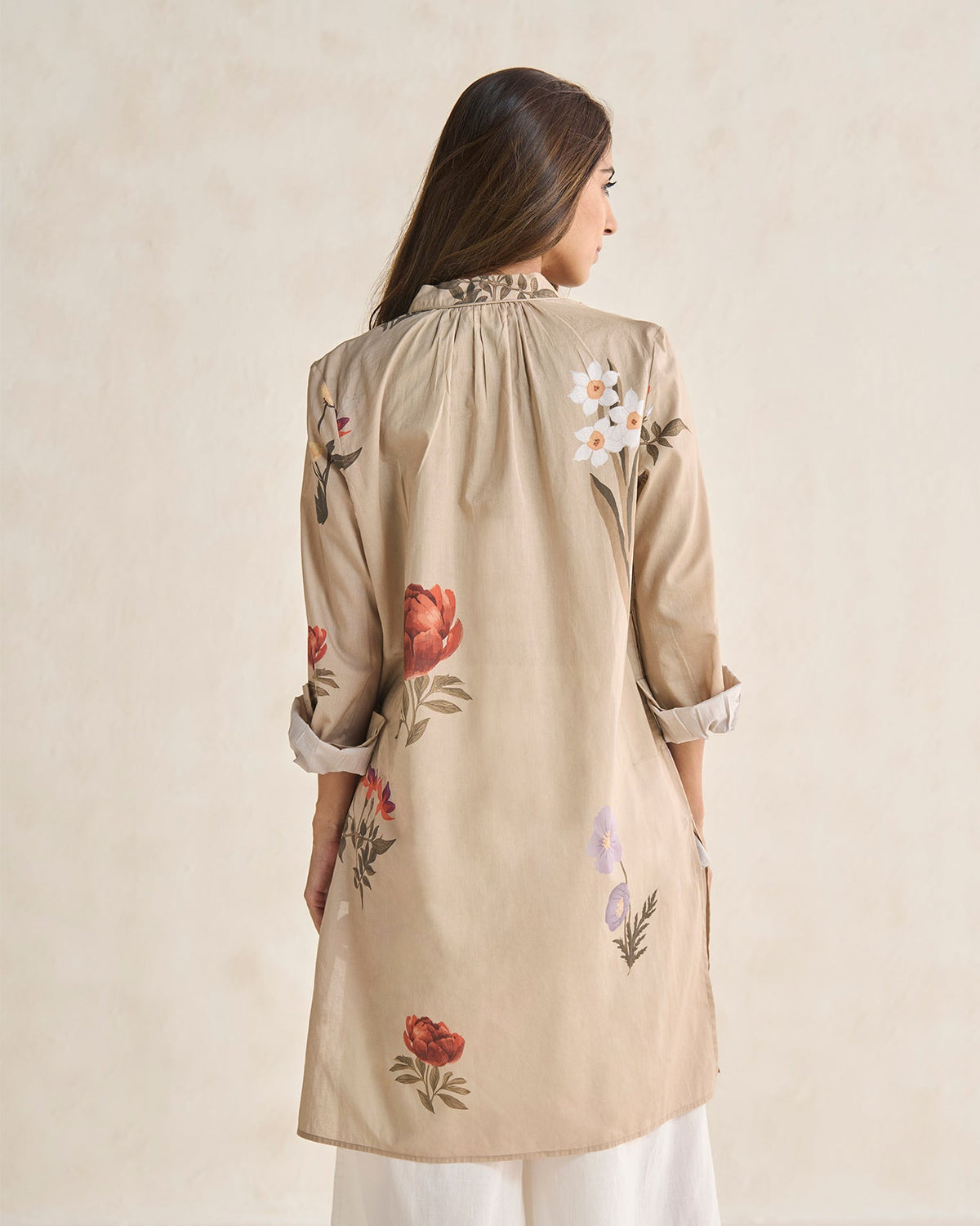 Back of a beige Boribo Highland kurta with red peony and white daffodil motifs worn by a person.