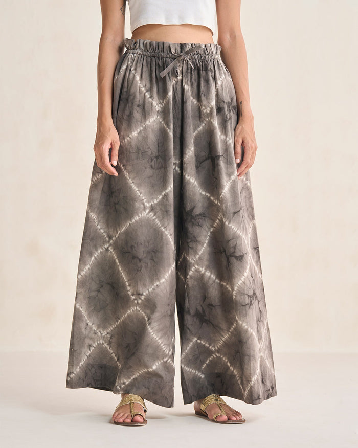 Person wearing brown Paperbag Pants in a tie-dye print with a drawstring waist.