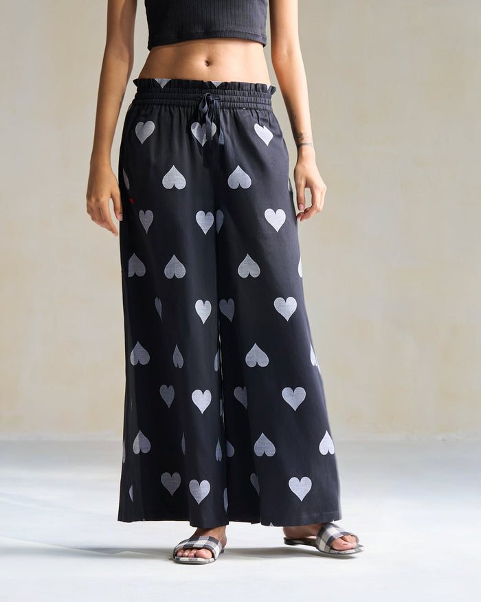 Person wearing black Nova Pants printed with grey hearts.