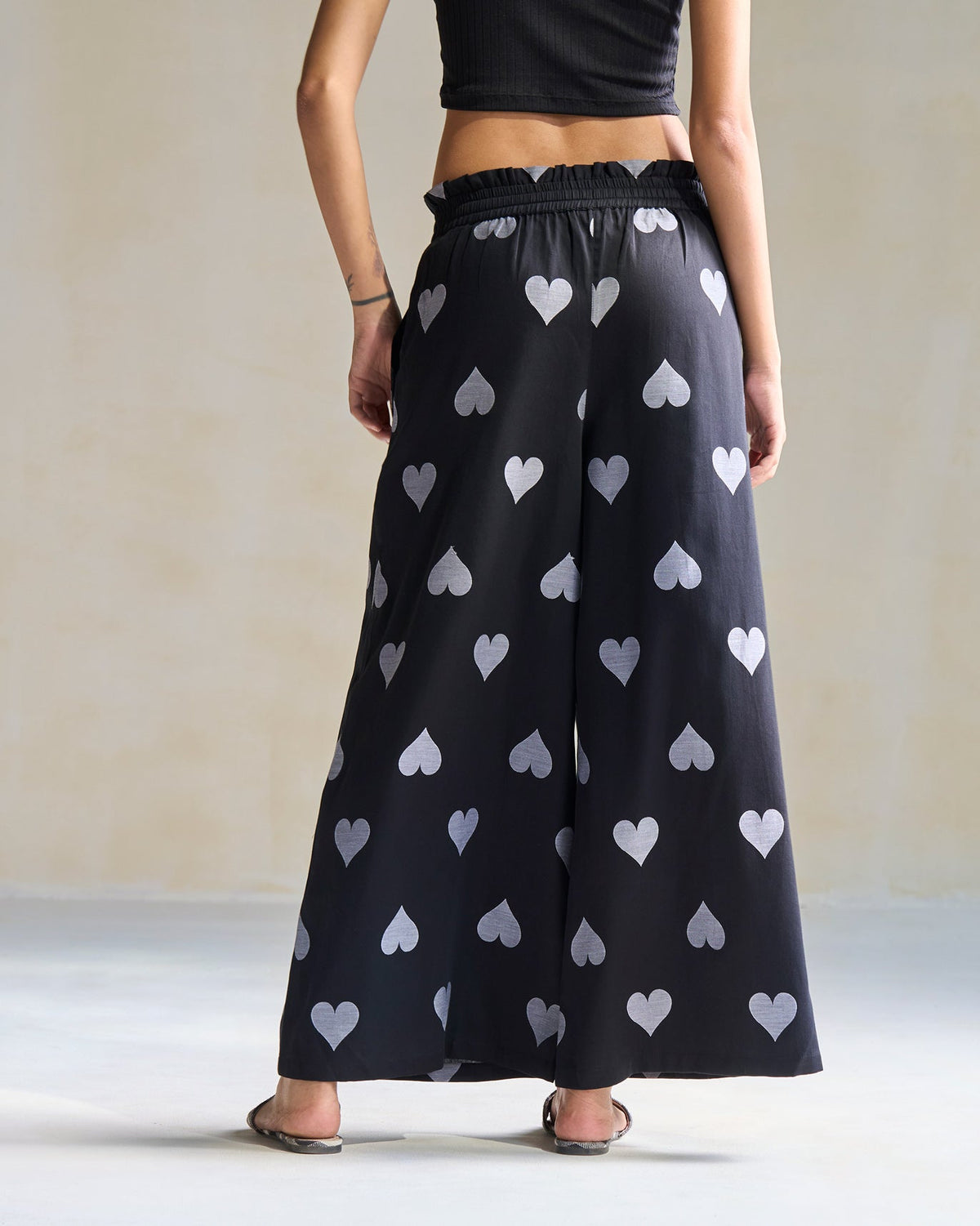 Back of black Nova Pants printed with grey hearts worn by a person.