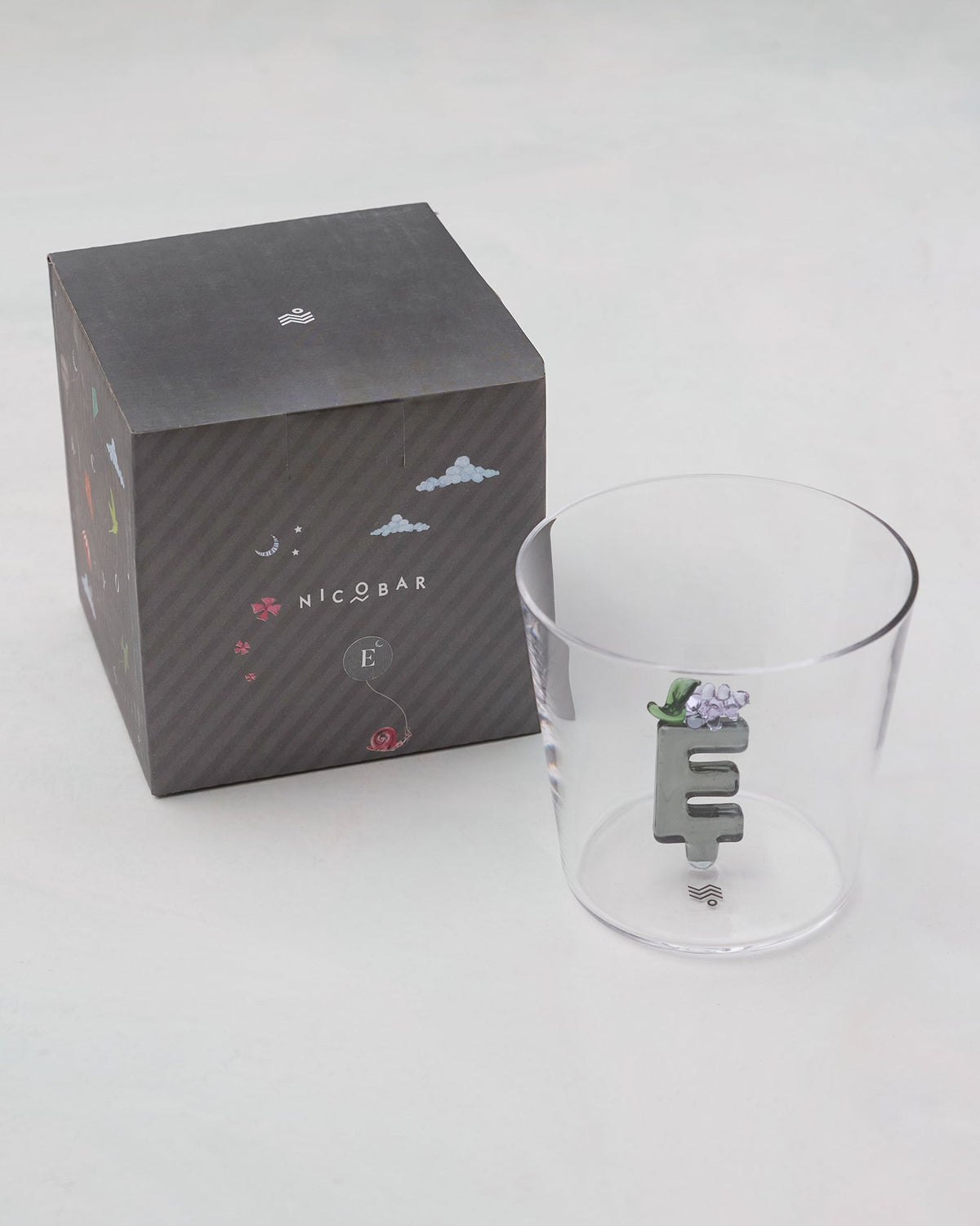 Clear Alphabet glass with a 3D letter E beside a charcoal Nicobar gift box.