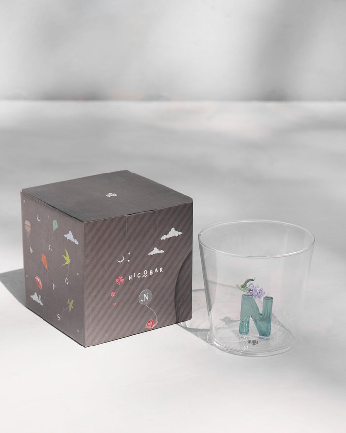 Alphabet glass with a teal letter N beside its charcoal Nicobar gift box.